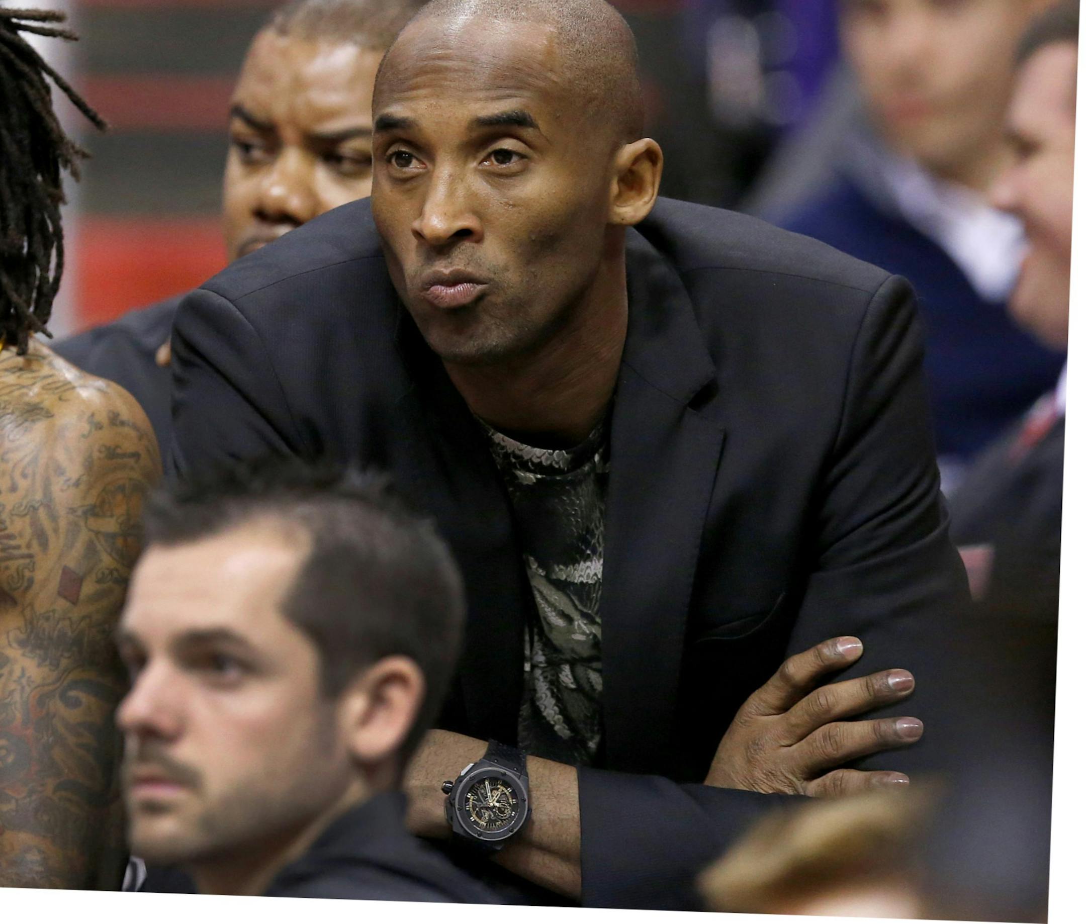 Injjured Los Angeles Lakers player Kobe Bryant, right, sits on the end of the team bench next to Jordan Hill, left, during the first half of an NBA basketball game against the Phoenix Suns on Wednesday, Jan. 15, 2014, in Phoenix. (AP Photo/Ross D. Franklin)