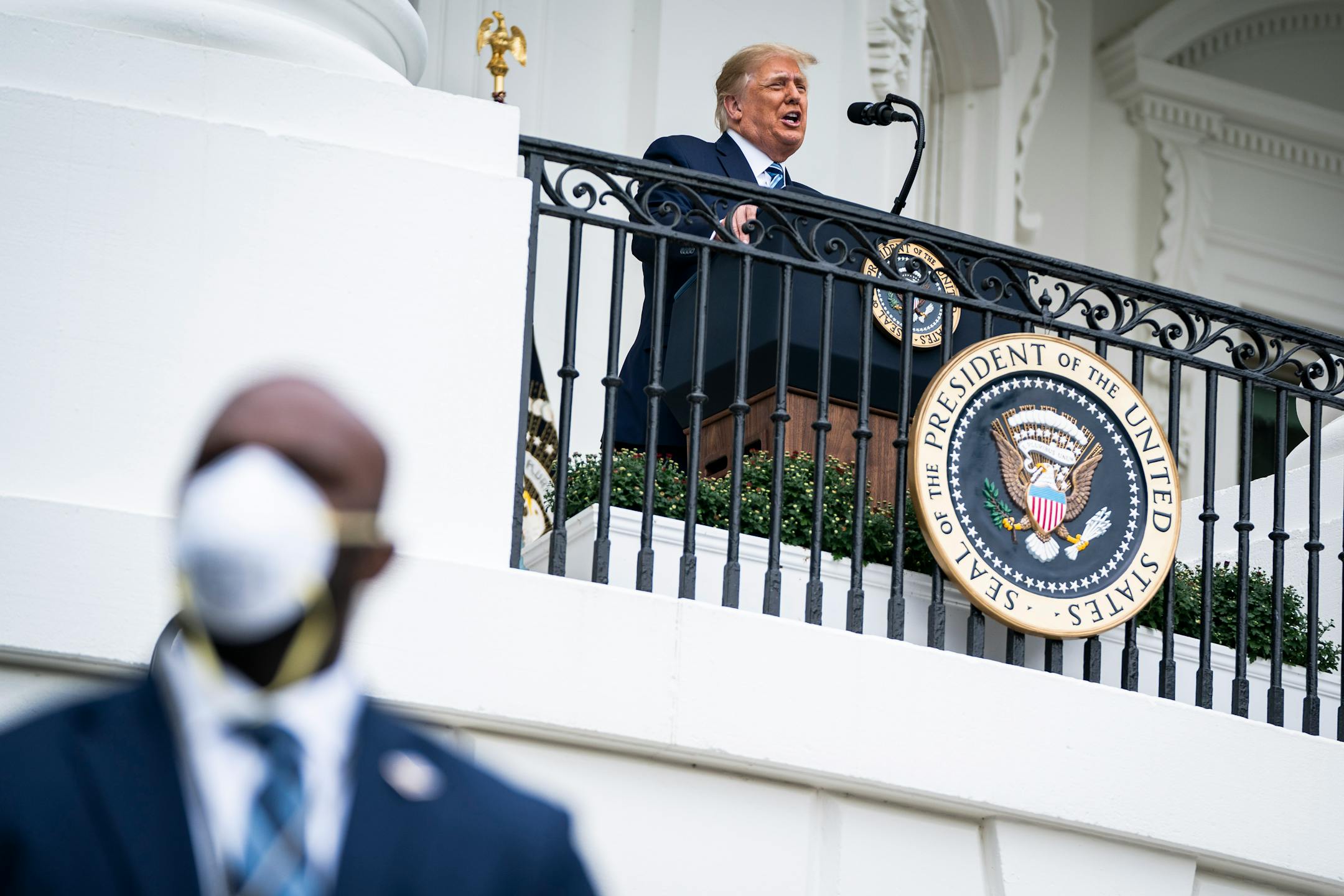 A Secret Service agent stands guard as then-President Donald Trump speaks to supporters from a White House balcony on Oct. 10 after testing positive for the coronavirus. MUST CREDIT: Washington Post photo by Jabin Botsford.