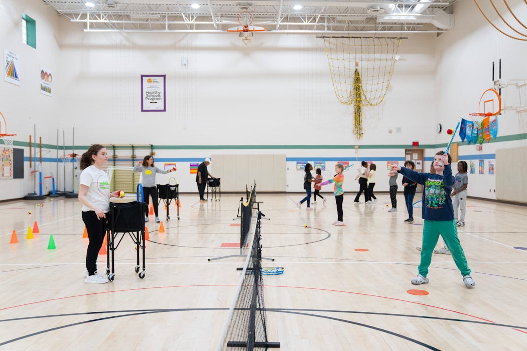 Aislinn Hogoboom, a tennis instructor, watches as Oliver Knox-Reeve practices an overhead swing during an InnerCity Tennis-led physical education class at Bryn Mawr Elementary School in Minneapolis on Tuesday.