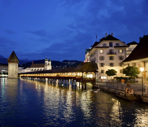 The Chapel Bridge with the Water Tower at the river Reuss in the centre of Lucerne, Switzerland, 19 July 2013. In the back is the Jesuit Church. Photo