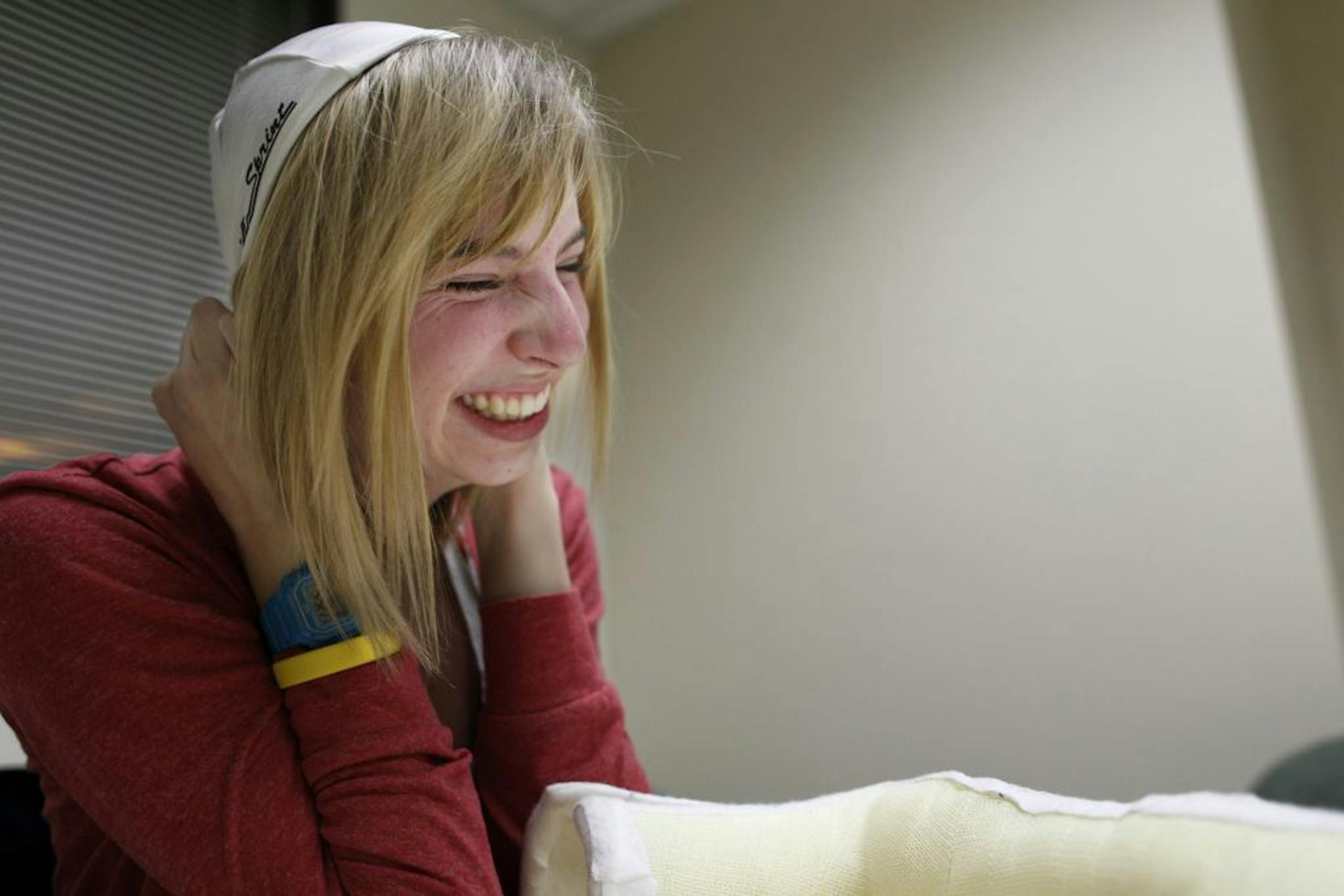 At Gillette Children's Clinic in Burnsville, Maddy Evans of Lakeville puts on the cap she wore during her electric brain stimulation therapy two years ago. On the table is the cast that was put on her dominant hand for two weeks so she would be forced to use the hand that was affected by the stroke. She credits the therapy for helping her make better use of both hands: i.e. the ability to put on a cap with two hands instead of relying on the one dominant hand.