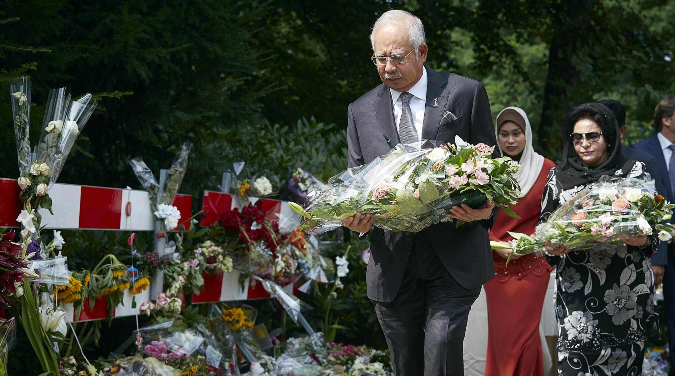 Malaysian Prime Minister Najib Razak, foreground and his wife Datin Sri Rosmah Mansor, right, lay flowers among other floral tributes, outside a military barracks where forensic experts are working to identify bodies and human remains recovered from the wreckage of Flight 17, in the central city of Hilversum, Netherlands, Thursday, July 31, 2014. Razak is making his first official visit to the Netherlands in the wake of the Malaysia Airlines Flight 17 disaster, in which an ill-fated passenger je