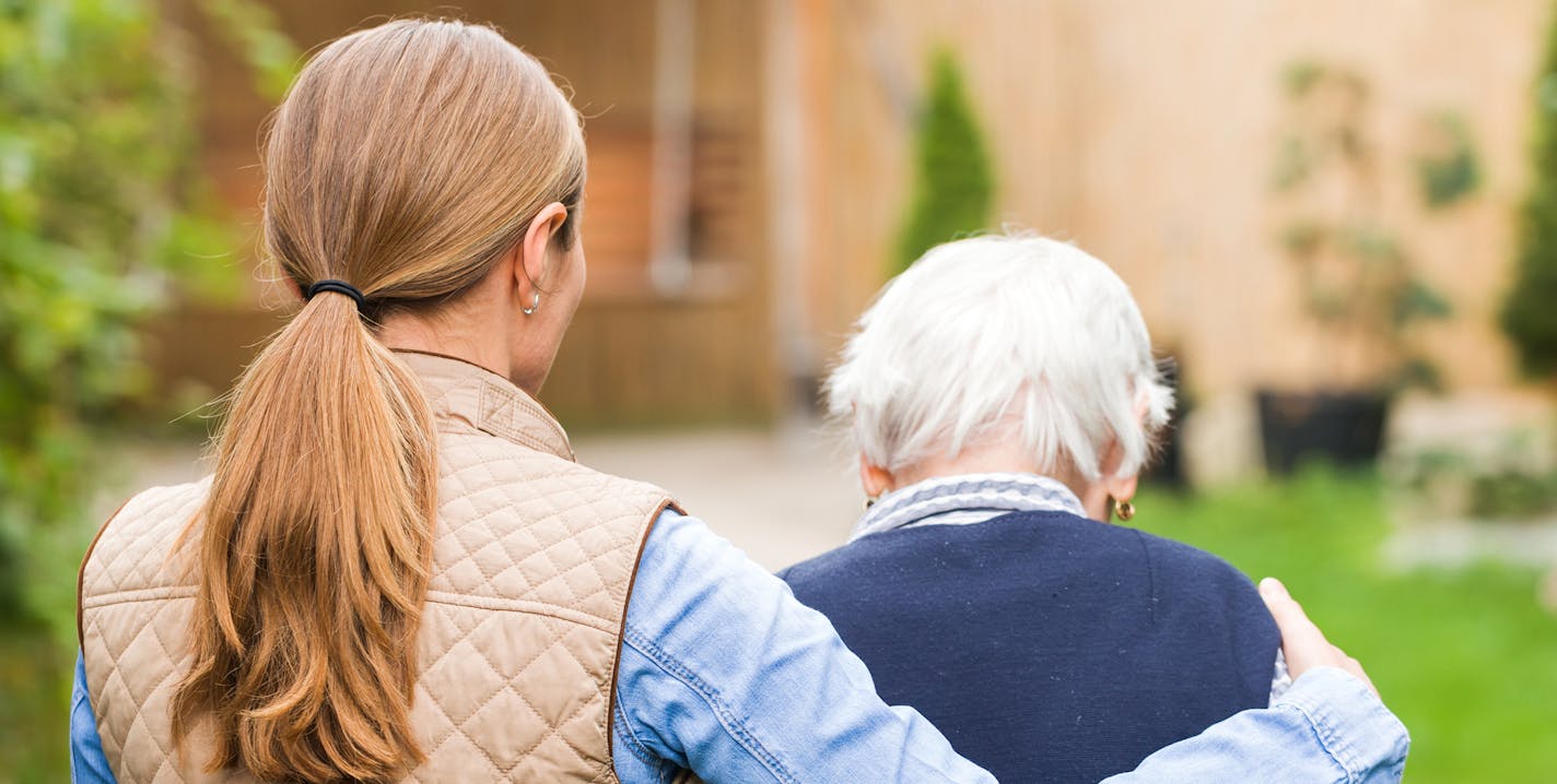 Young carer walking with the elderly woman in the park