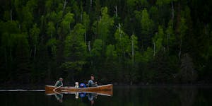 Tony Jones, left, his yellow Lab Crosby, and Bob Timmons paddled over a still Mountain Lake on June 14 toward their portages to Moose Lake.
