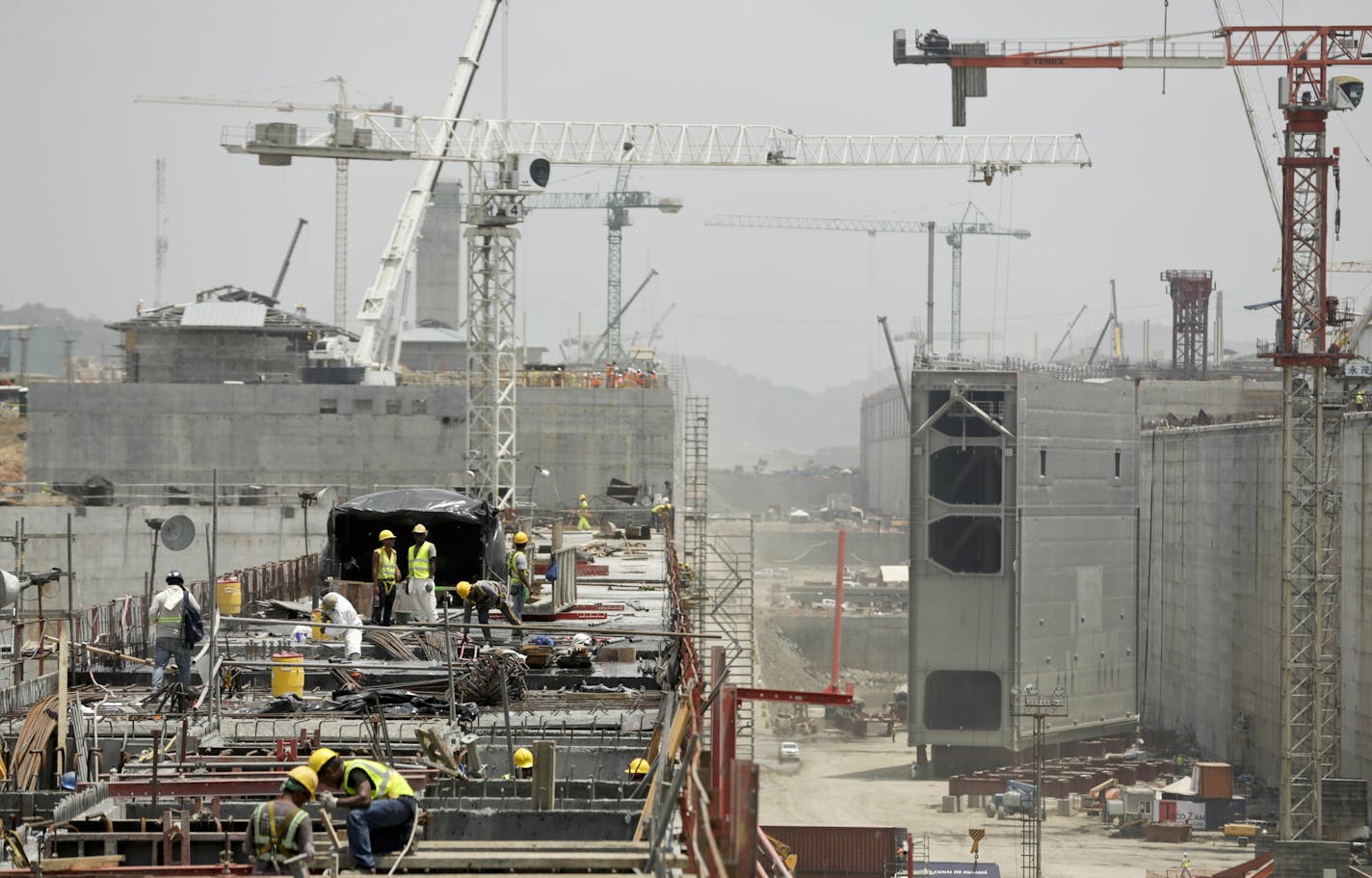 Construction crews work on the the Panama Canal expansion project new set of locks, while the last rolling gate is installed in Cocoli, near Panama City, Tuesday, April 28, 2015. The Panama Canal Authority supervised the installation of the last of 16 giant lock gates that are a key part of the waterway's multibillion-dollar expansion. The construction of the third set of locks will allow the passage of Post-Panamax vessels or container ships much too big to fit through the Panama Canal's old lo