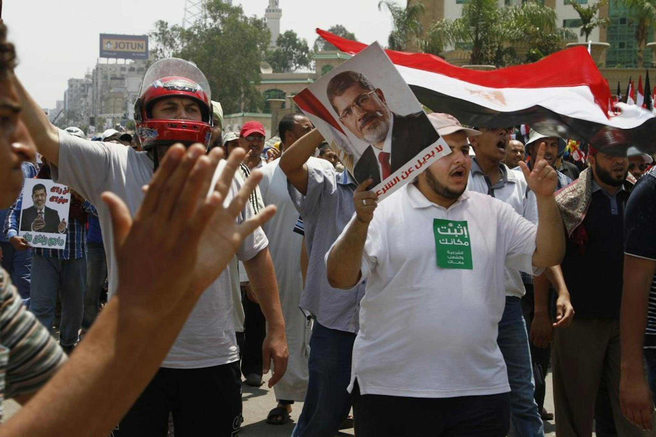 Supporters of Egypt's ousted President Mohammed Morsi wave Egyptian flags and his picture at a sit-in in Nasser City, suburb of Cairo, Egypt, Sunday, July 7, 2013.