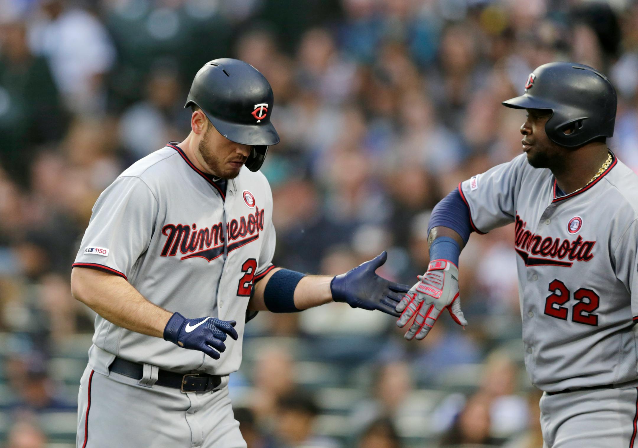 Minnesota Twins' C.J. Cron, left, is greeted by Miguel Sano, right, after hitting a solo home run, his second homer of the night, against the Seattle Mariners during the third inning of a baseball game Saturday, May 18, 2019, in Seattle. (AP Photo/John Froschauer)