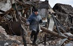Inna, 71, carries possessions rescued from the rubble of her house which was destroyed by a Russian drone attack in a residential neighbourhood, in Za