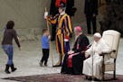 A child plays with a Swiss guard in the Paul VI Hall at the Vatican, Wednesday, Nov. 28, 2018. Pope Francis has praised the freedom, albeit undiscipli