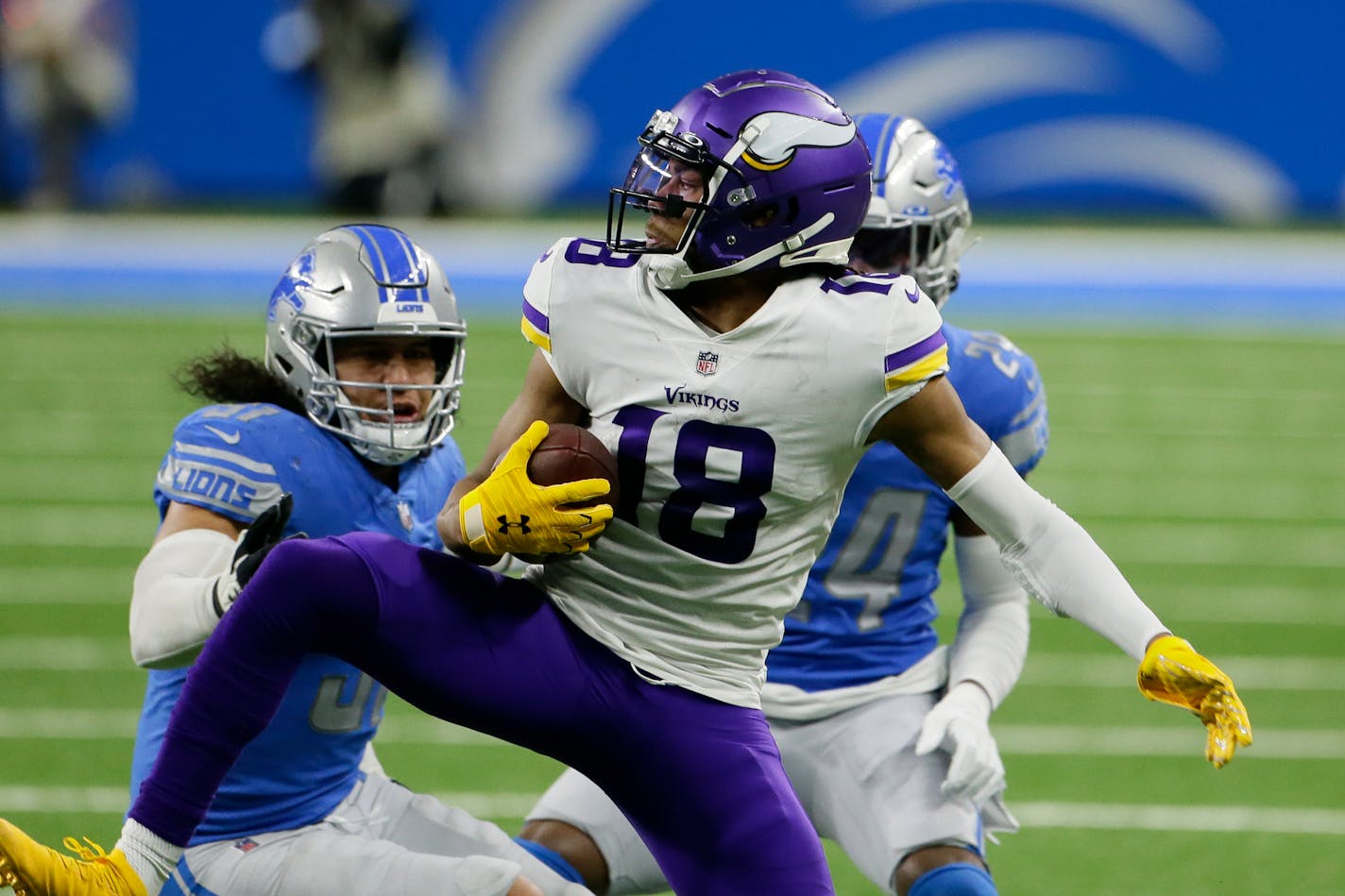 Vikings wide receiver Justin Jefferson makes a catch as Lions outside linebacker Jahlani Tavai, left, and cornerback Amani Oruwariye defend during the first half