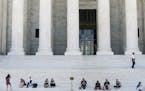 Visitors sit on the steps of the U.S. Supreme Court building on Capitol Hill in Washington, where justices issued decisions Thursday on several cases.