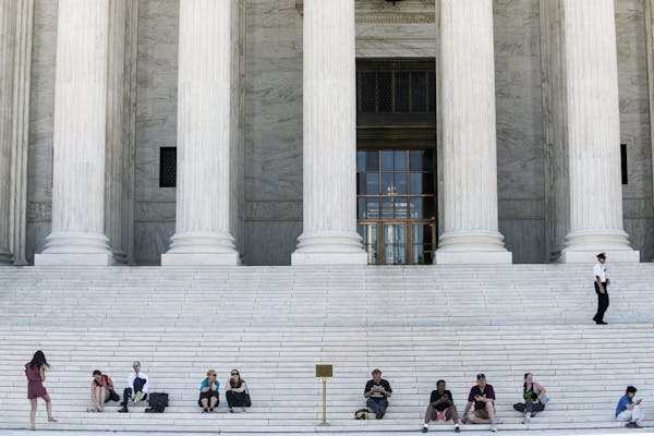 Visitors sit on the steps of the U.S. Supreme Court building on Capitol Hill in Washington, where justices issued decisions Thursday on several cases.