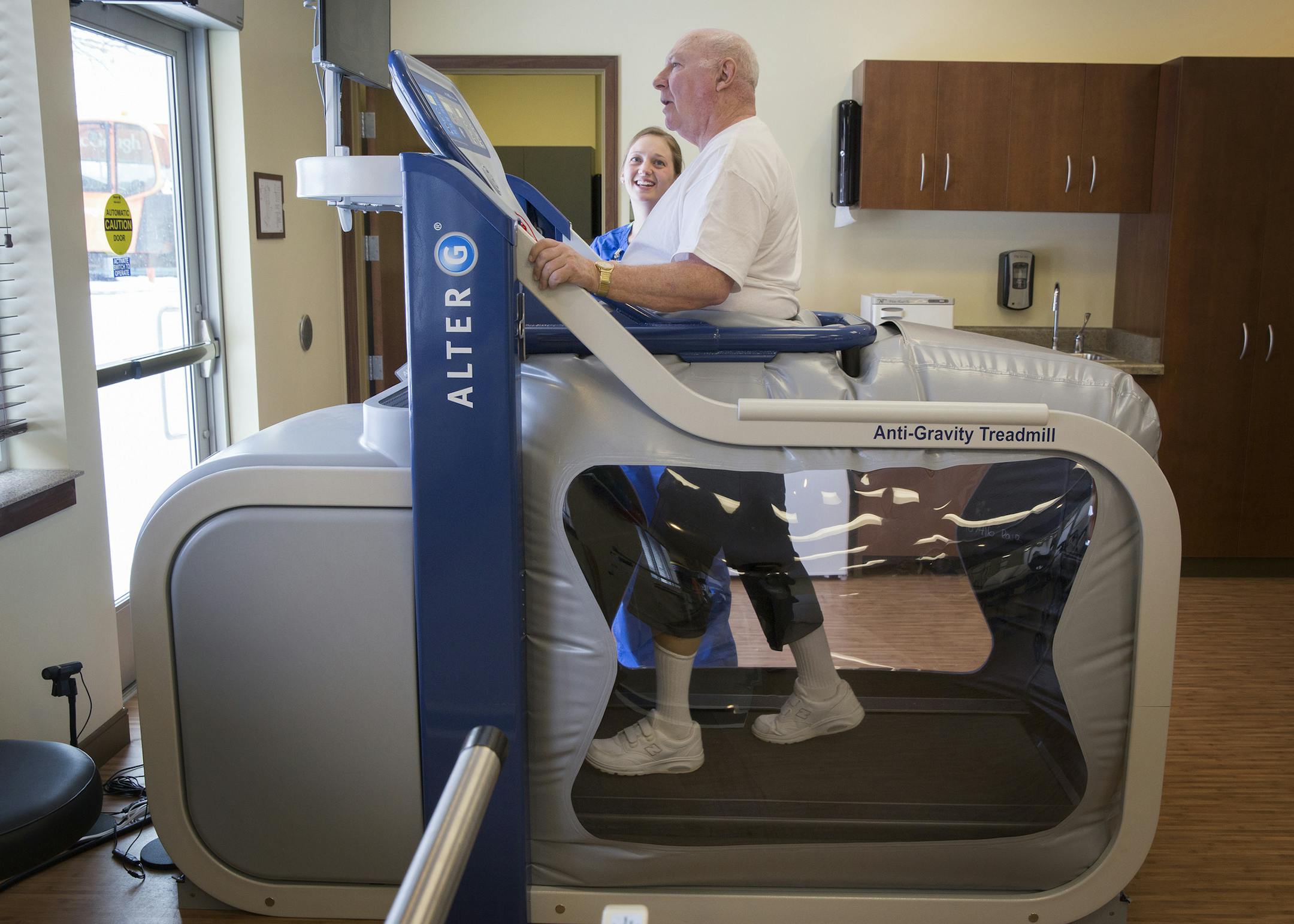Dave Ryan of St. Anthony, who is recovering from a stroke that affected the left side of his body, walks on an AlterG Anti-Gravity Treadmill with the help of physical therapist Mary Horoshak at Interlude Restorative Suites in Fridley on Tuesday, March 3, 2015. ] LEILA NAVIDI leila.navidi@startribune.com / BACKGROUND INFORMATION: The AlterG Anti-Gravity Treadmill reduces gravity's impact by letting the user select any weight between 20% and 100% of their body weight while using the machine. The m