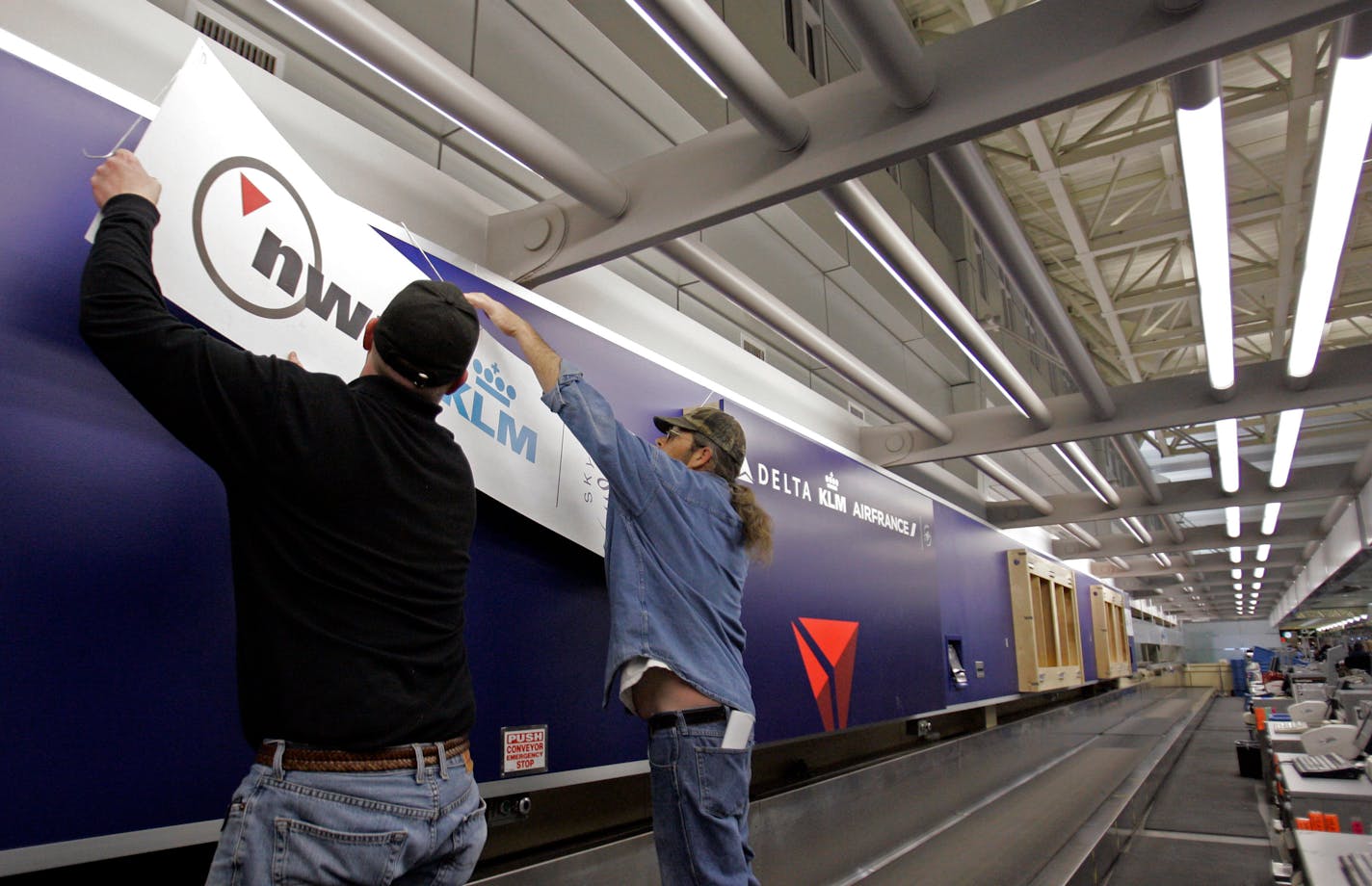 Shannon King, left, and Brian Vosberg take down the Northwest sign after placing a new Delta sign on the Northwest ticket counter at Minneapolis-St. Paul International Airport Monday, March 30, 2009 in Minneapolis, Minn. (AP Photo/Kiichiro Sato)