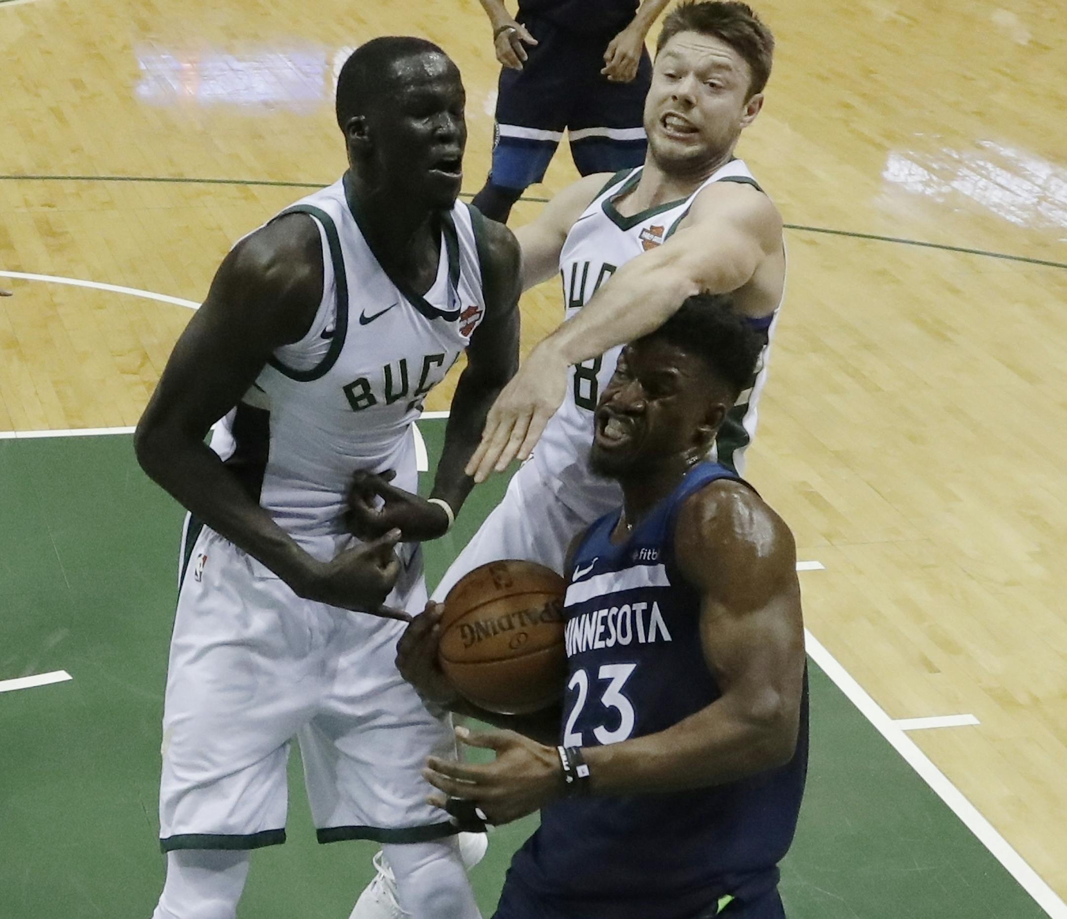 Minnesota Timberwolves' Jimmy Butler is fouled as he drives past Milwaukee Bucks' Matthew Dellavedova and Eric Bledsoe during the first half of an NBA basketball game Thursday, Dec. 28, 2017, in Milwaukee. (AP Photo/Morry Gash)