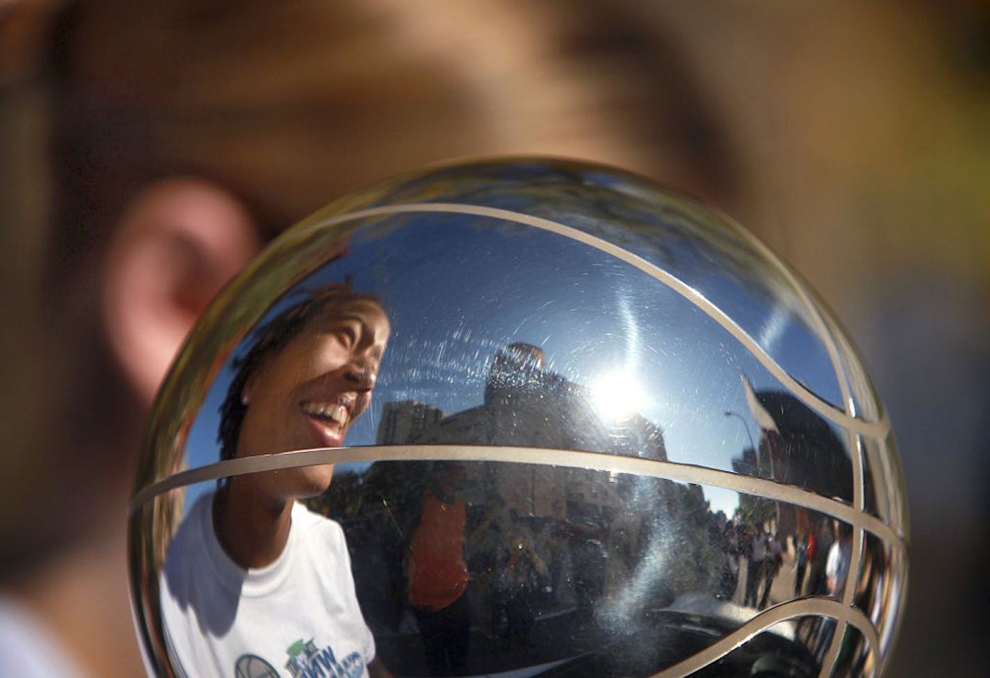 The smiling face of Minnesota Lynx's Seimone Augustus is reflected in the WNBA basketball championship trophy as she carried it in a parade, Tuesday, Oct. 11, 2011, in Minneapolis. The team was honored with a downtown parade and a rally at Target Center, with an estimated 15,000 people lined up along the route and about 5,000 fans inside the arena to cheer and hear from the players.(AP Photo/Star Tribune, Jim Gehrz) ST. PAUL OUT MAGS OUT MINNEAPOLIS-AREA TV OUT