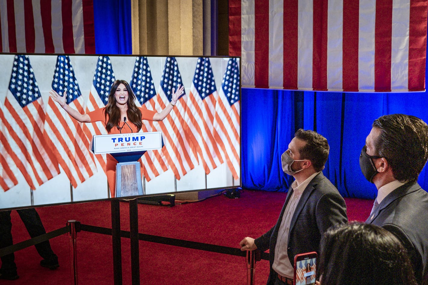 Donald Trump Jr., right, watches Kimberly Guilfoyle address the Republican National Convention from the Andrew W. Mellon Auditorium in Washington, on Monday, Aug. 24, 2020. (Pete Marovich/The New York Times)