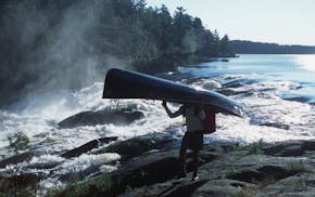 Steve Piragis of Ely MN portages his canoe around roaring Curtain Falls on Crooked Lake along the Minnesota-Ontario border during a late-summer bounda