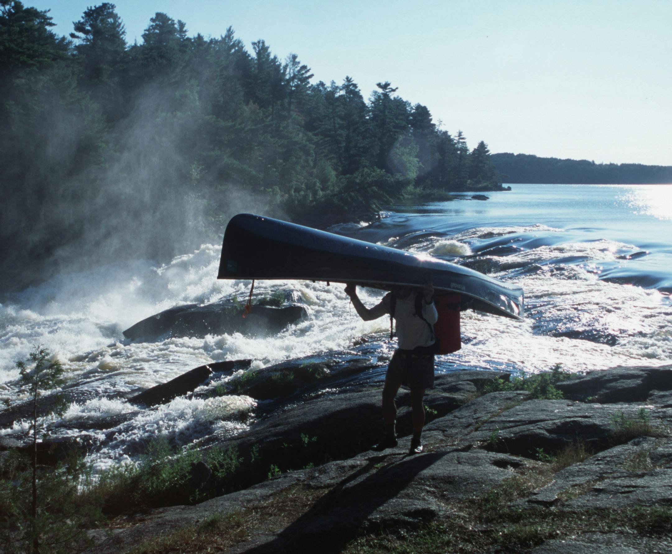 Steve Piragis of Ely MN portages his canoe around roaring Curtain Falls on Crooked Lake along the Minnesota-Ontario border during a late-summer boundary waters trek. This photo ran in color Sunday Sept 9, 2001, page C20. Photo by Star Tribune outdoors writer Doug Smith. ORG XMIT: MIN2013083013065214 ORG XMIT: MIN1308301308090068 ORG XMIT: MIN1405161416080157