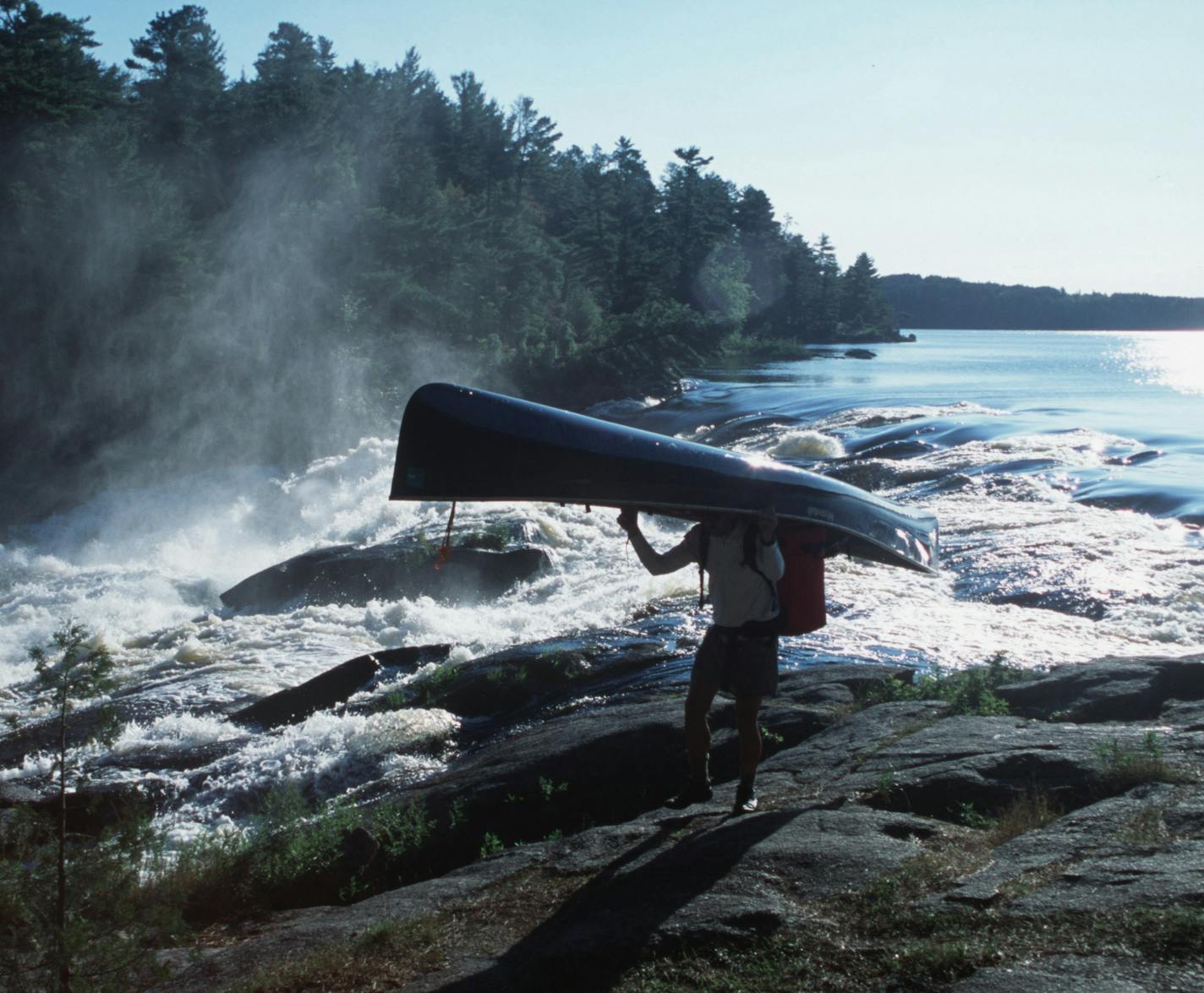 Steve Piragis of Ely MN portages his canoe around roaring Curtain Falls on Crooked Lake along the Minnesota-Ontario border during a late-summer boundary waters trek. This photo ran in color Sunday Sept 9, 2001, page C20. Photo by Star Tribune outdoors writer Doug Smith. ORG XMIT: MIN2013083013065214 ORG XMIT: MIN1308301308090068 ORG XMIT: MIN1405161416080157