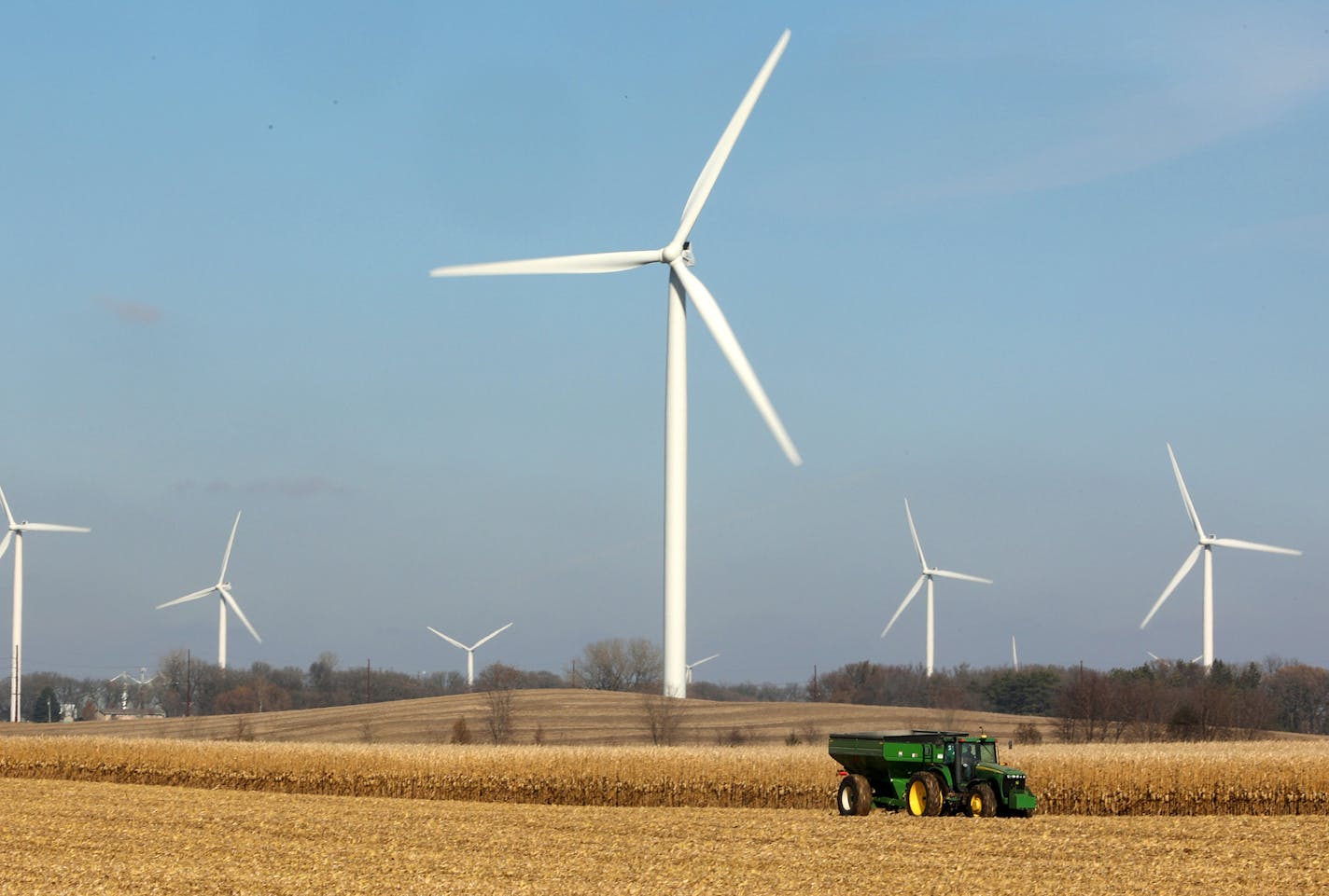 Windmills dot the landscape as a farmer harvested corn near Alden, Minn. Scenes like this have caused residents south of the area such as Dorenne Hansen to become more vocal in their opposition to the proposed project.