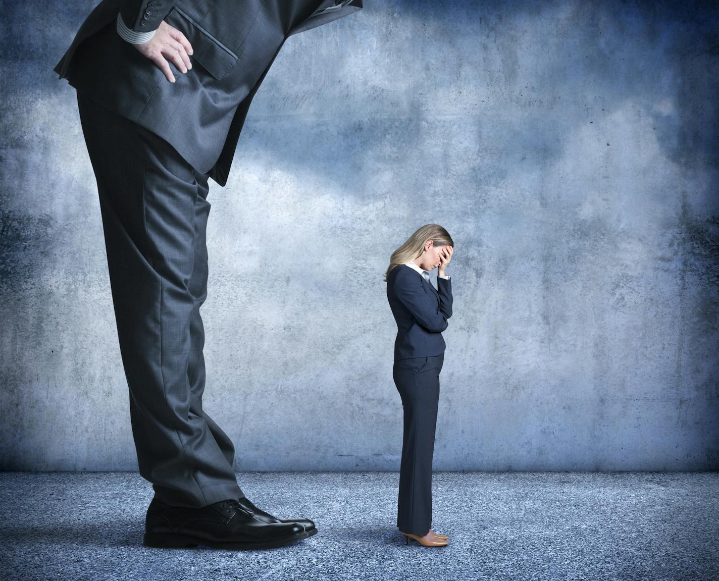 A businesswoman stands with her head buried in her hands as she tries to withstand the stress of gender or workplace discrimination from her much larger boss.