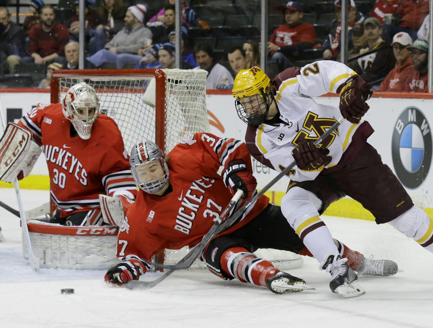 Minnesota forward Hudson Fasching, right, controls the puck in front of Ohio State forward Nick Schilkey (37) as Ohio State goalie Christian Frey (30) covers the net during the second period of a college hockey game in the semifinals of the Big 10 Conference tournament in St. Paul, Minn., Friday, March 21, 2014. (AP Photo/Ann Heisenfelt)