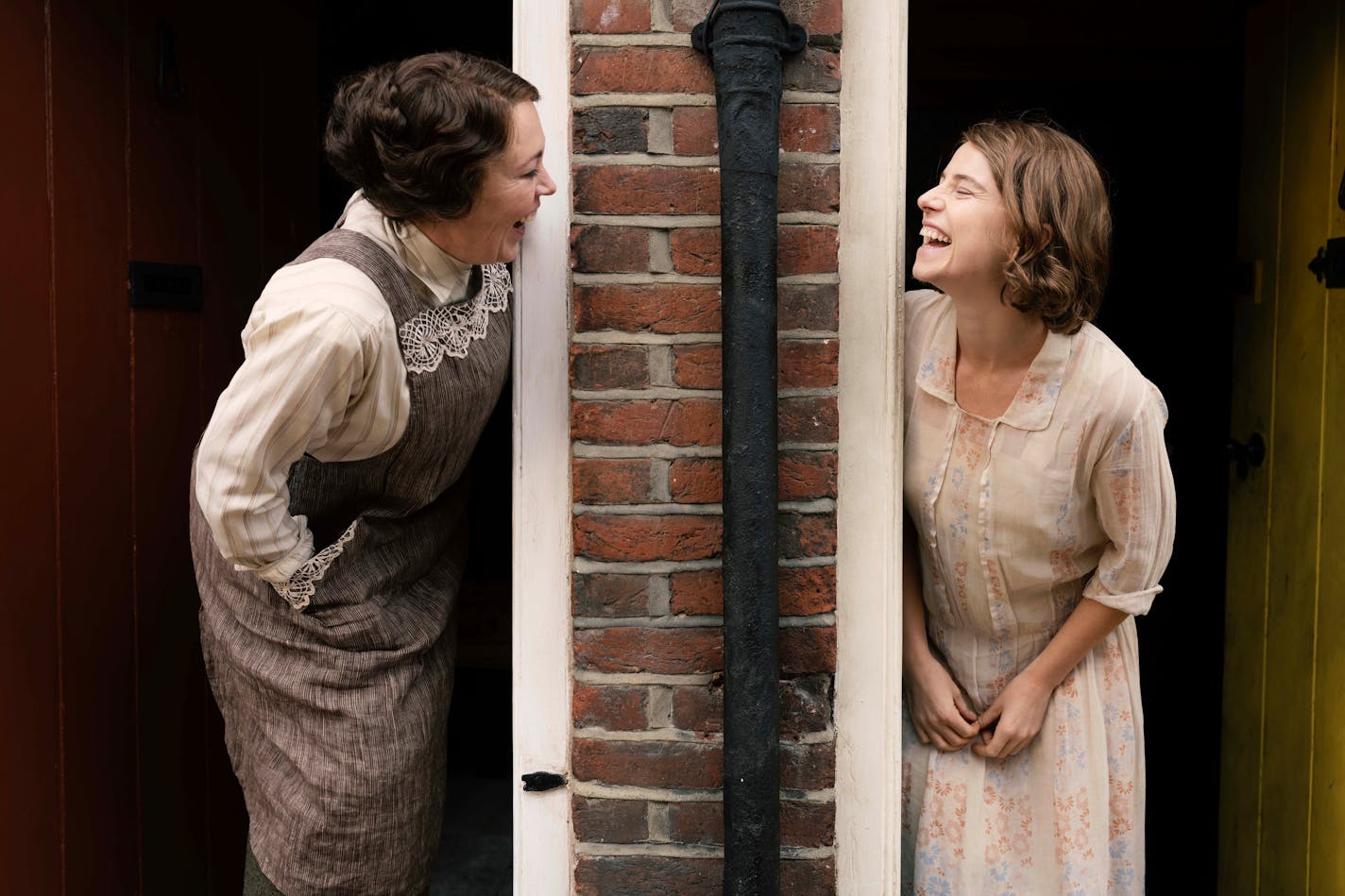 image of two women, leaning out their front doors and laughing