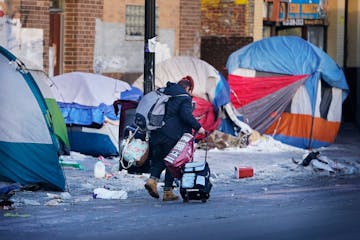 A former resident of a homeless encampment along Bloomington Ave. S., near 26th St. E. moves her belongings before city officials cleared the camp Thu