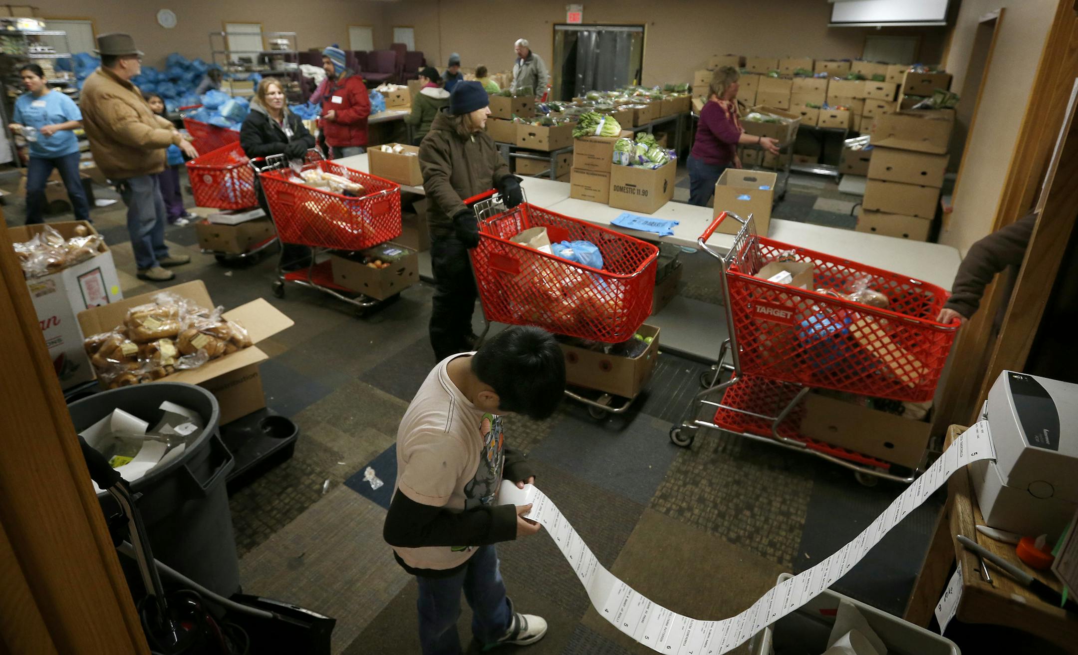 Volunteer Jorge Rivera ,8, prepared labels that would be put on grocery carts for their recipients as other volunteers prepared groceries at the Fruit of the Vine food shelf in Burnsville on Tuesday. ] CARLOS GONZALEZ cgonzalez@startribune.com - November 25, 2014, Burnsville, Minn., Fruit of the Vine food shelf