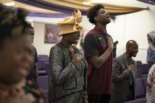 Daniel Oturu and his parents, Deborah and Francis, stand in prayer at Mountain of Fire and Miracles church.