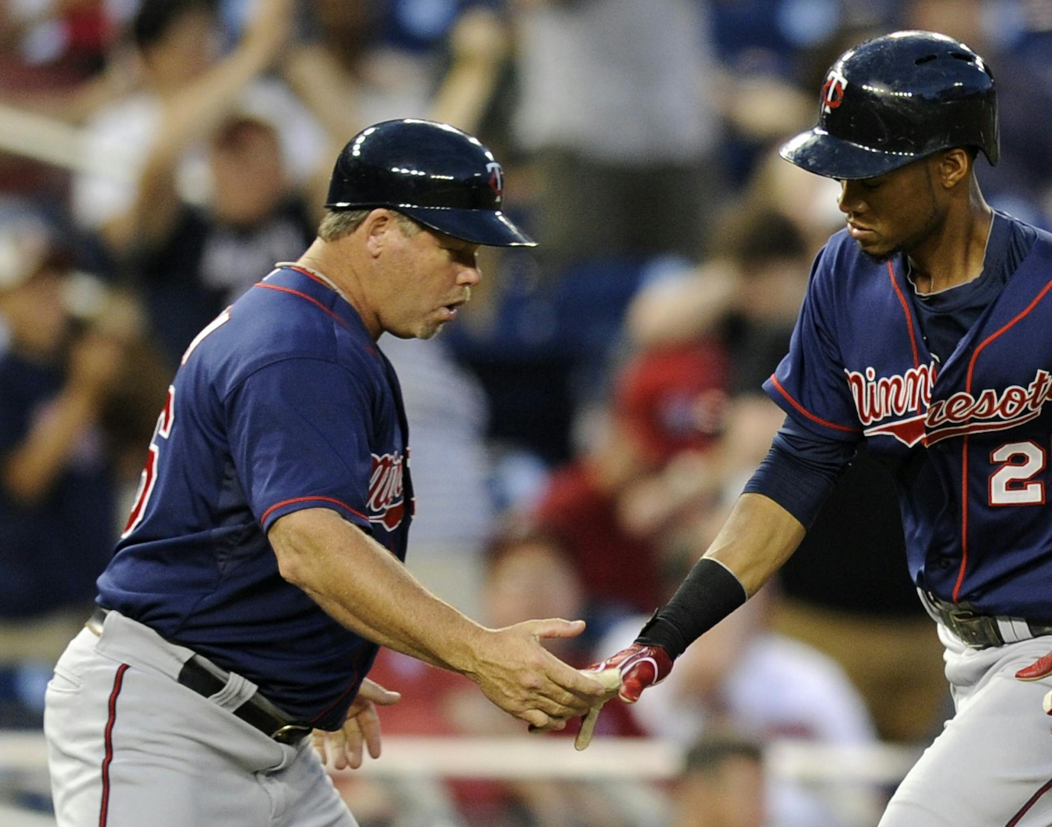 Minnesota Twins' Pedro Florimon (25) is greeted by third base coach Joe Vavra (46) after he hit a two-run home run against the Washington Nationals during the third inning of the second baseball game of a day-night interleague doubleheader, Sunday, June 9, 2013, in Washington. (AP Photo/Nick Wass) ORG XMIT: MIN2013061420561275