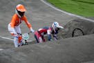 Alise Willoughby of the United States retrieves her bike after crashing, as Merel Smulders of the Netherlands passes on the left, in the BMX Racing se
