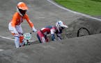Alise Willoughby of the United States retrieves her bike after crashing, as Merel Smulders of the Netherlands passes on the left, in the BMX Racing se