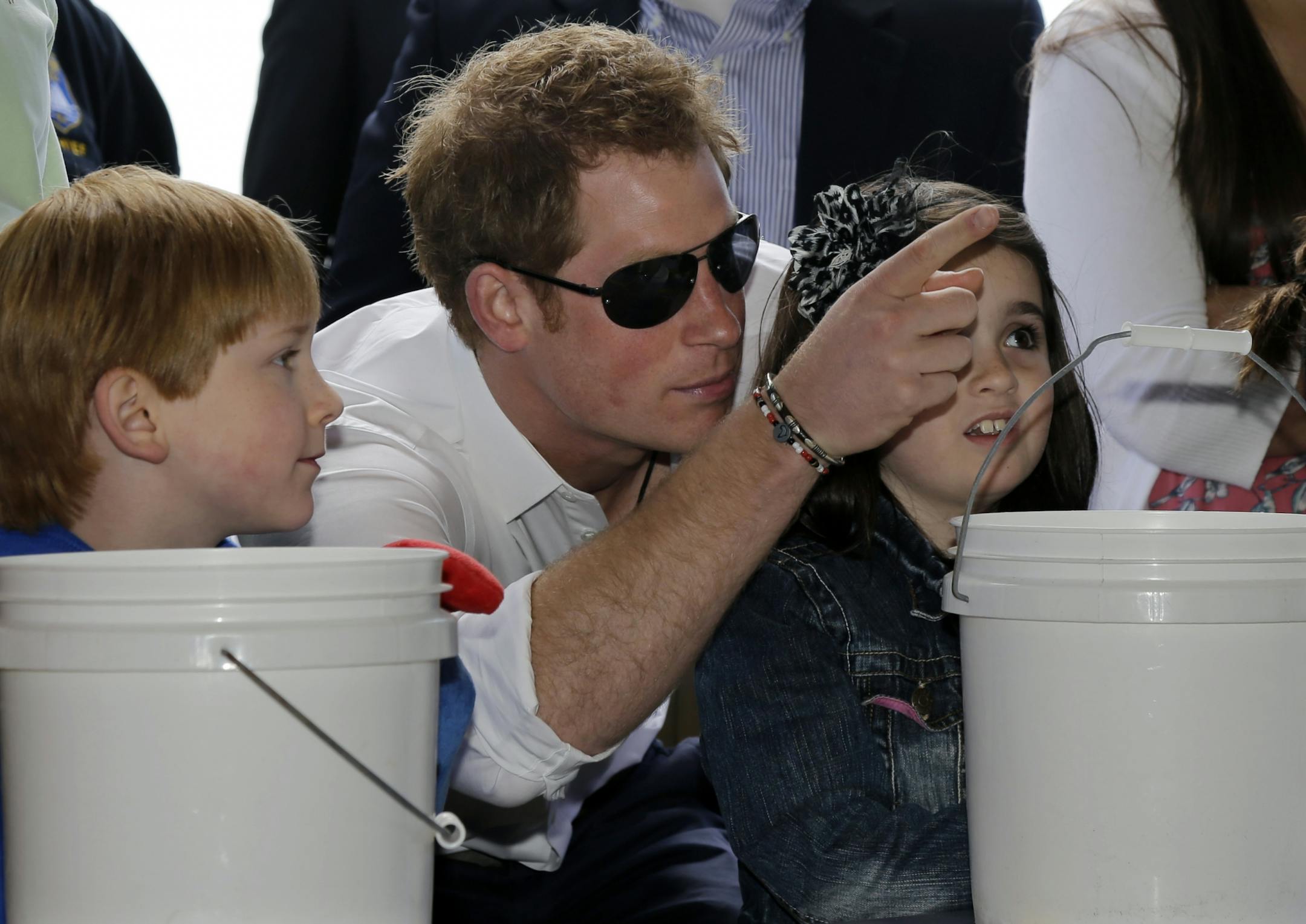 Michael Vanover, 7, left, looks on as Britain's Prince Harry helps Taylor Cirigliano, 11, right, pick a prize at a Ball Toss game on the boardwalk, while visiting the area hit by Superstorm Sandy, Tuesday, May 14, 2013, in Seaside Heights, N.J. Prince Harry began a tour of New Jersey�s storm-damaged coastline, inspecting dune construction, walking past destroyed homes and shaking hands with police and other emergency workers. New Jersey sustained about $37 billion worth of damage from the storm.
