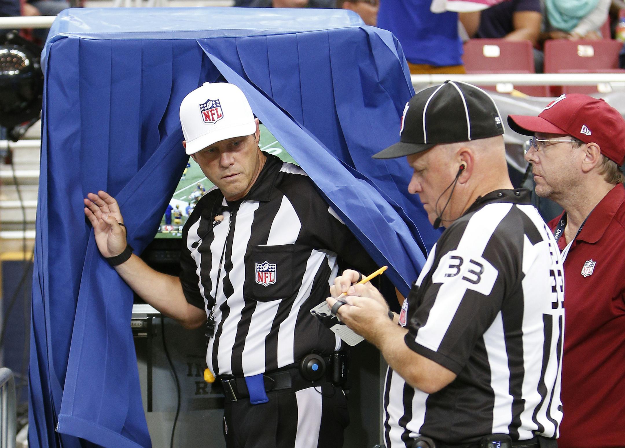 Referee Craig Wrolstad, left, leaves the instant replay monitor in the third quarter of an NFL football game between the St. Louis Rams and the San Francisco 49ers Monday, Oct. 13, 2014, in St Louis. At right is field judge Steve Zimmer (33). (AP Photo/Scott Kane) ORG XMIT: MOMH1
