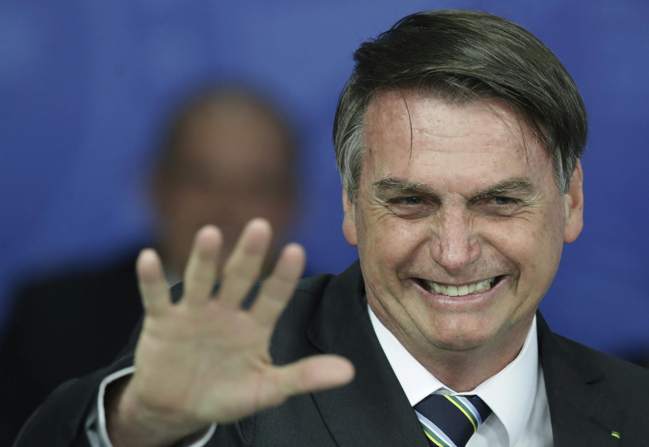 Brazil's President Jair Bolsonaro waves during an event at the Planalto Presidential Palace, in Brasilia, Brazil, Tuesday, April 30, 2019. Bolsonaro convened a meeting of top ministers to discuss the ongoing situation in Venezuela. (AP Photo/Eraldo Peres)