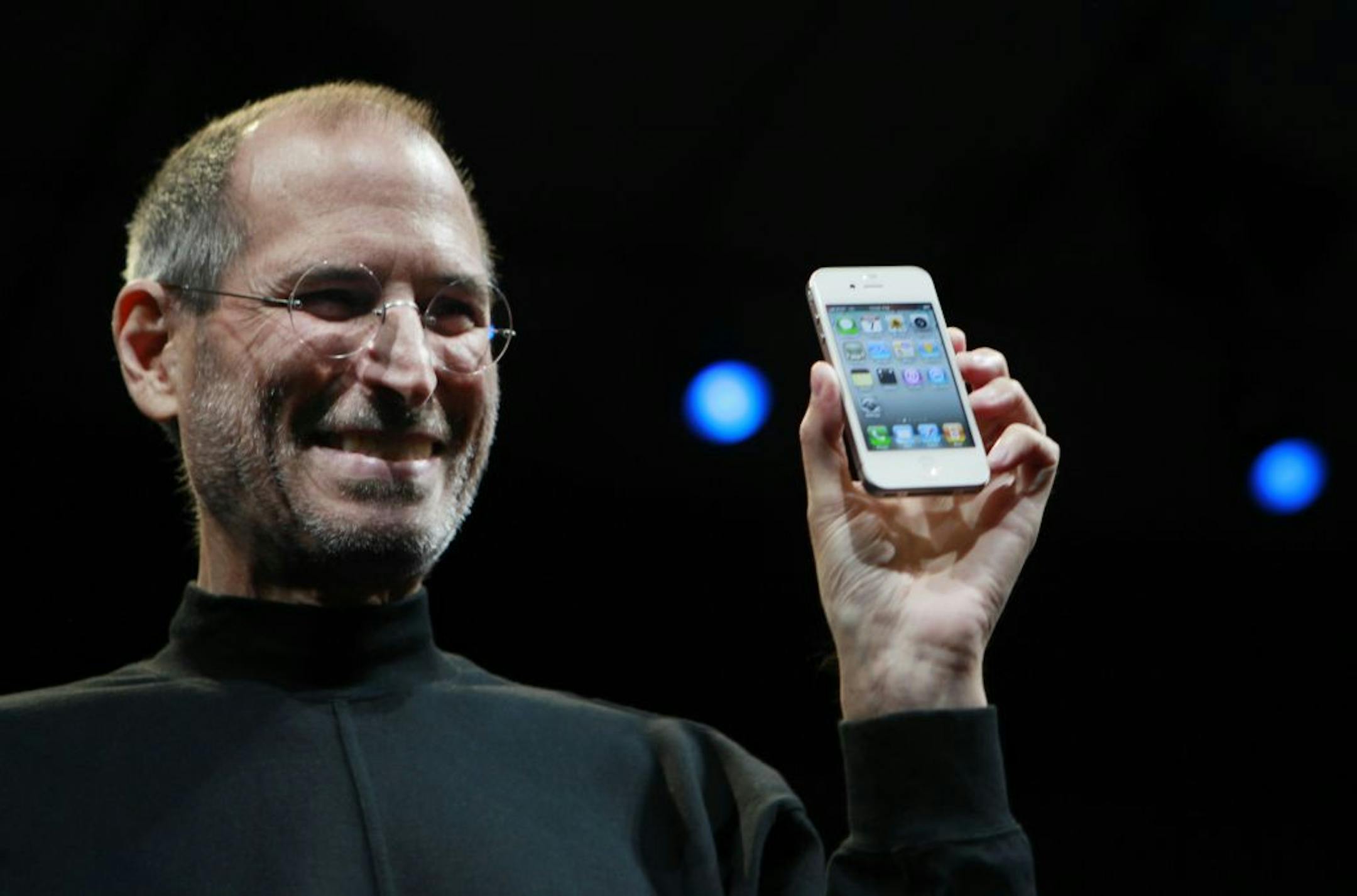 Apple CEO Steve Jobs smiles with a new iPhone at the Apple Worldwide Developers Conference in San Francisco in 2010.