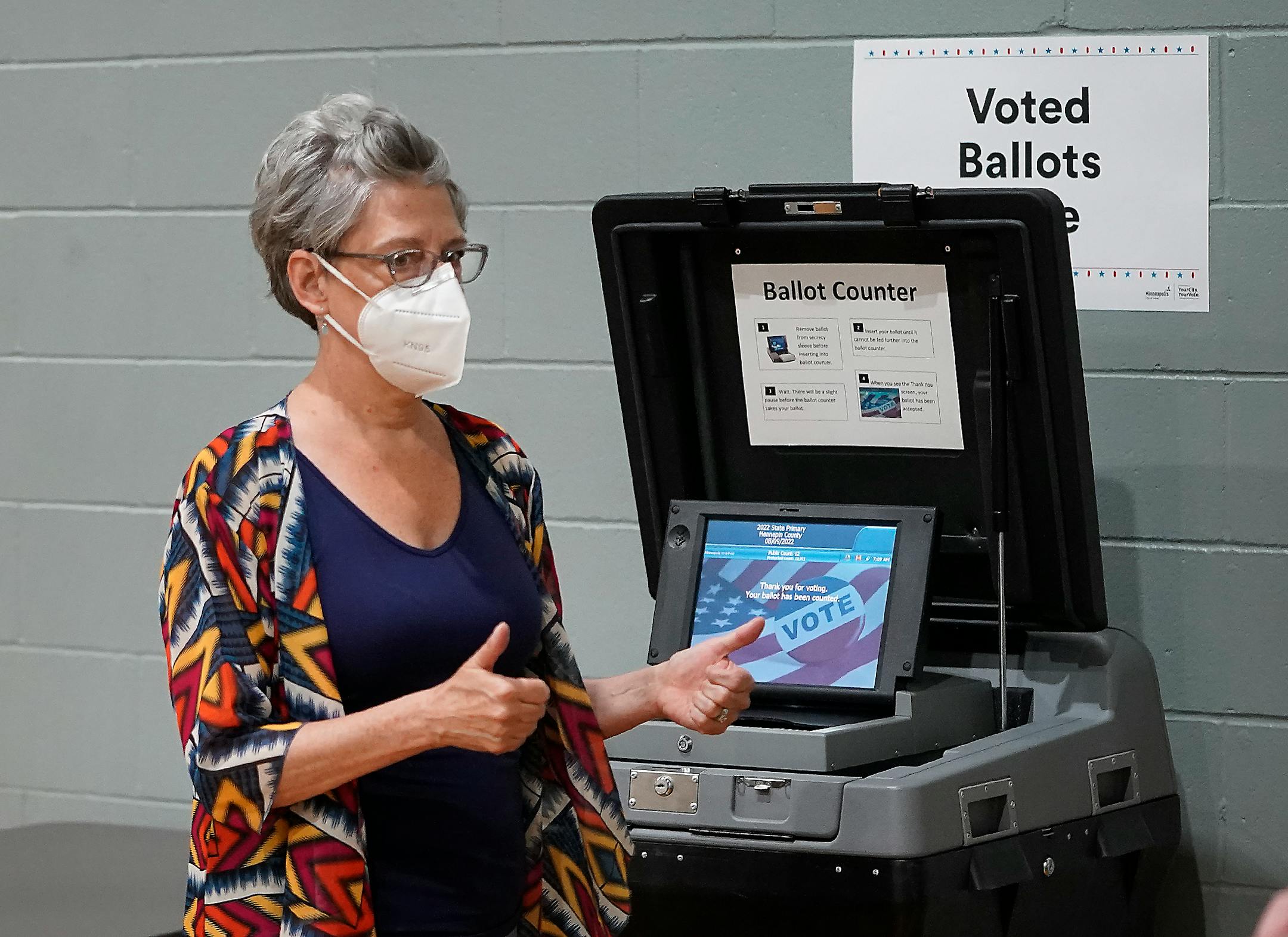 Voter Amy Dillahunt of Minneapolis gives a thumbs up to an election worker after her ballot was scanned and accepted at Powderhorn Park during the primary election that includes the 5th congressional district in Minneapolis.