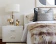 A brass table lamp is paired with a bold brass/gold accent piece to highlight a side table. (Scott Gabriel Morris/Handout/TNS)