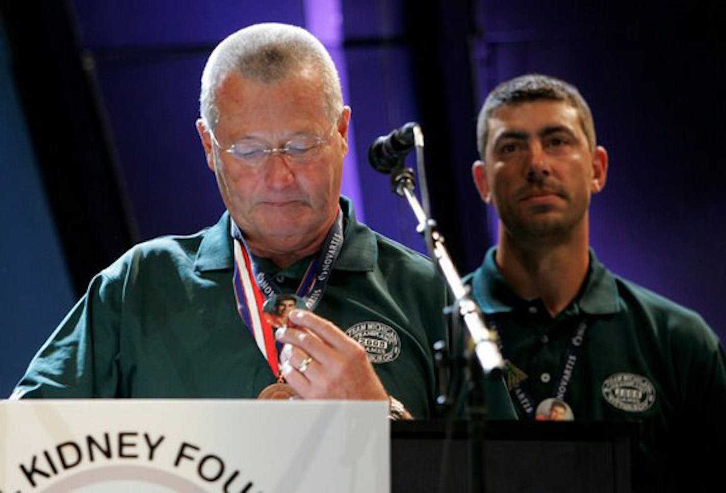 Terry Gould, a heart-transplant survivor, looking at the picture of Chase Coleman, whose picture was on the button Gould was looking at (while Chase's brother Lon looks on) from the Opening Ceremony Pittsburgh Transplant Games. At the Transplant games, Terry gave a speech about his situation with the Colemans.