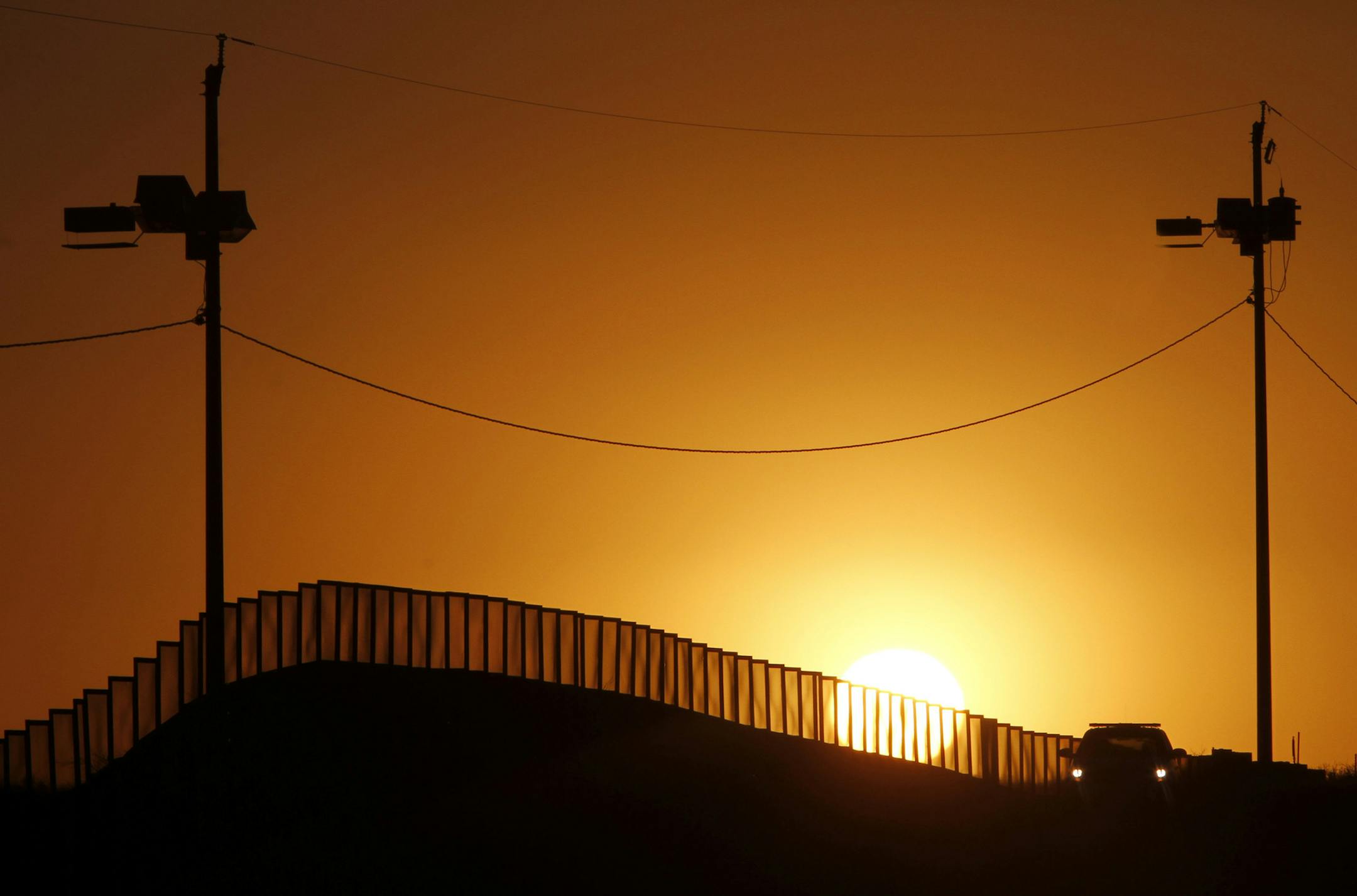 Sunset at the U.S.-Mexico border in Naco, Ariz., where a Border Patrol agent in his car keeps an eye on activity. (Don Bartletti/Los Angeles Times) ORG XMIT: 1191081