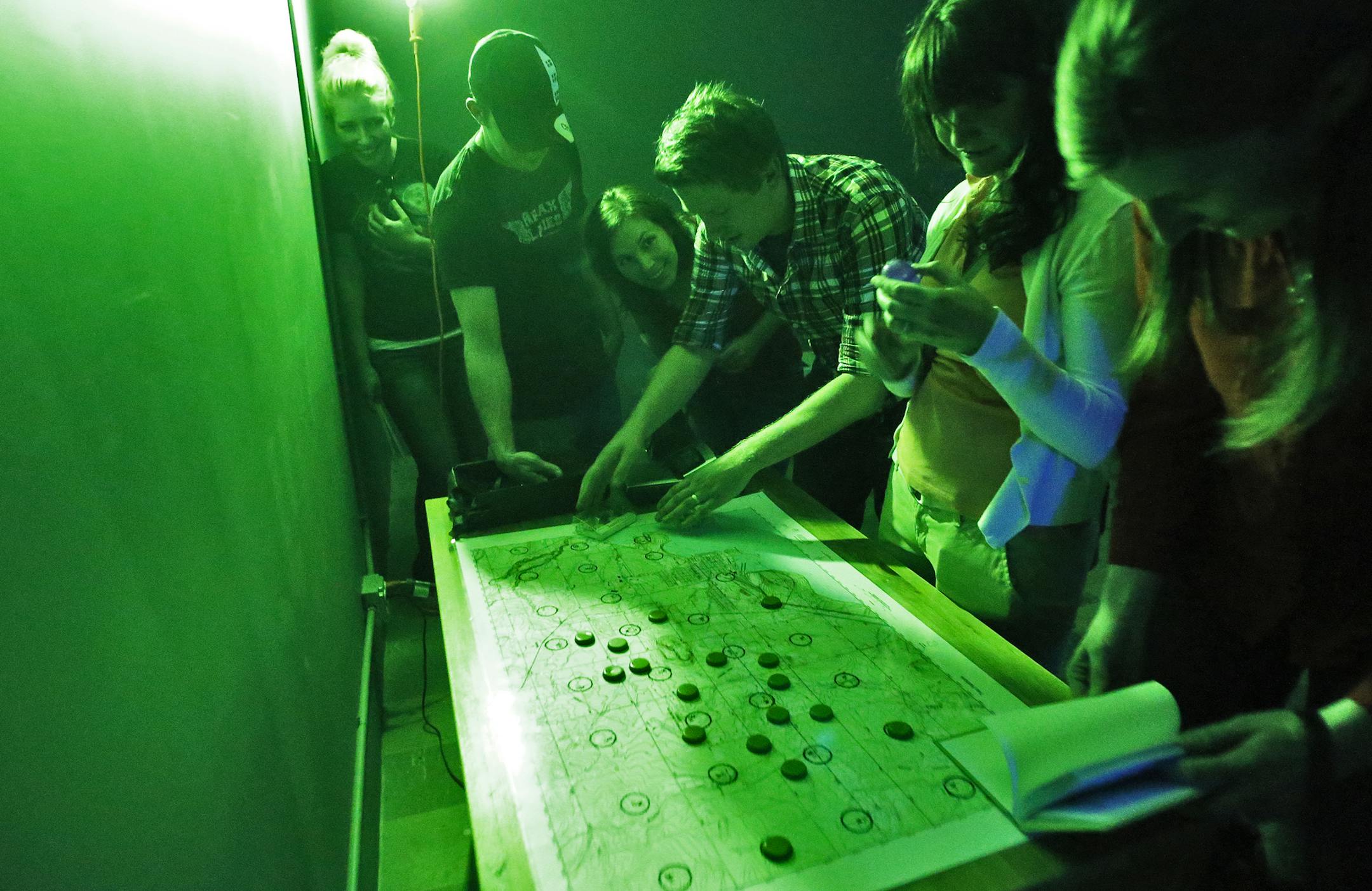 A group works on the various clues presented to them in an effort to find passage out of the riddle room. ] The Riddle Room Bunker in Minneapolis. (MARLIN LEVISON/STARTRIBUNE(mlevison@startribune.com)