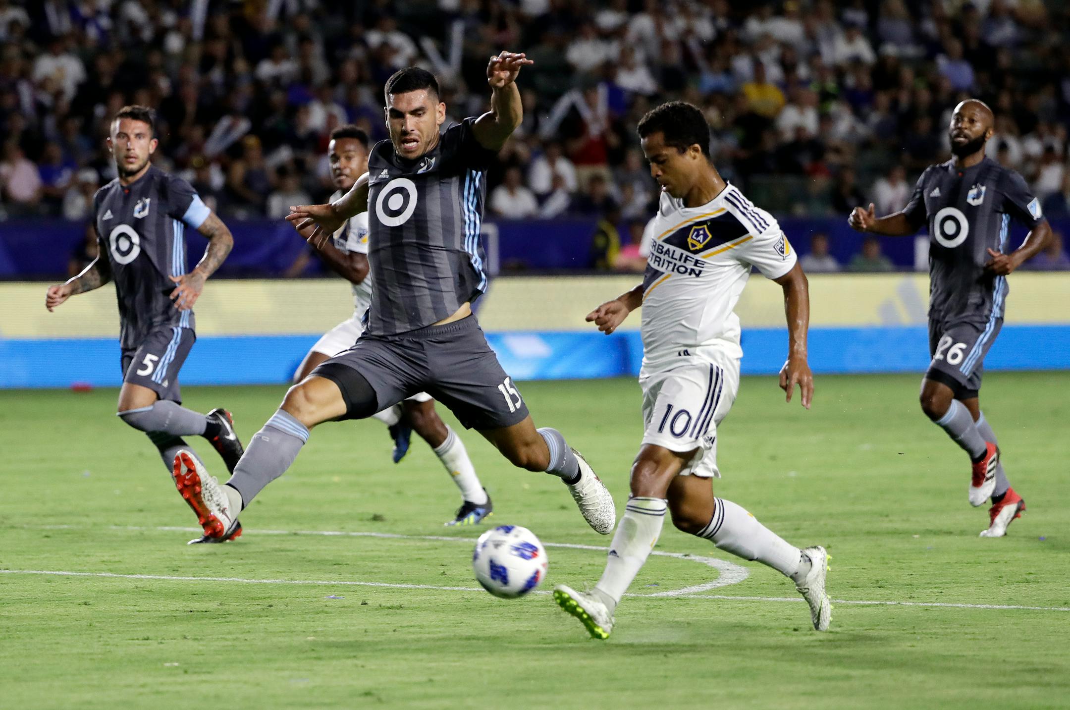 LA Galaxy forward Giovani dos Santos, right, shoots next to Loons defender Michael Boxall during the first half Saturday.