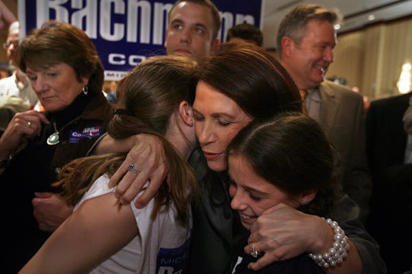 Michele Bachmann embraced Lexi, 11, and Cali Weddle, 9, of Andover. Bachmann's husband, Marcus, is at right at the Bloomington Sheraton GOP gathering.