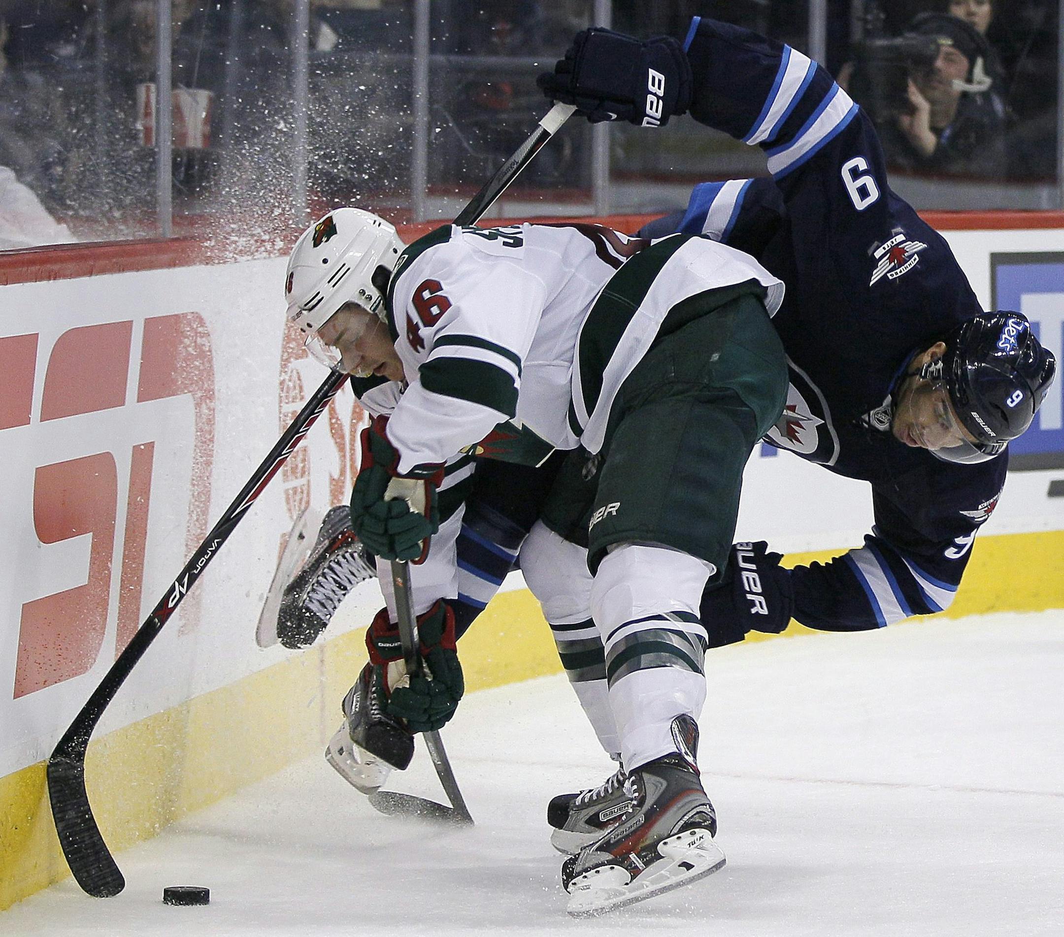 Winnipeg Jets' Evander Kane (9) gets dumped in Minnesota Wild's territory by Jared Spurgeon (46) during second-period NHL hockey game action in Winnipeg, Manitoba, Friday, Dec. 27, 2013. (AP Photo/The Canadian Press, John Woods)