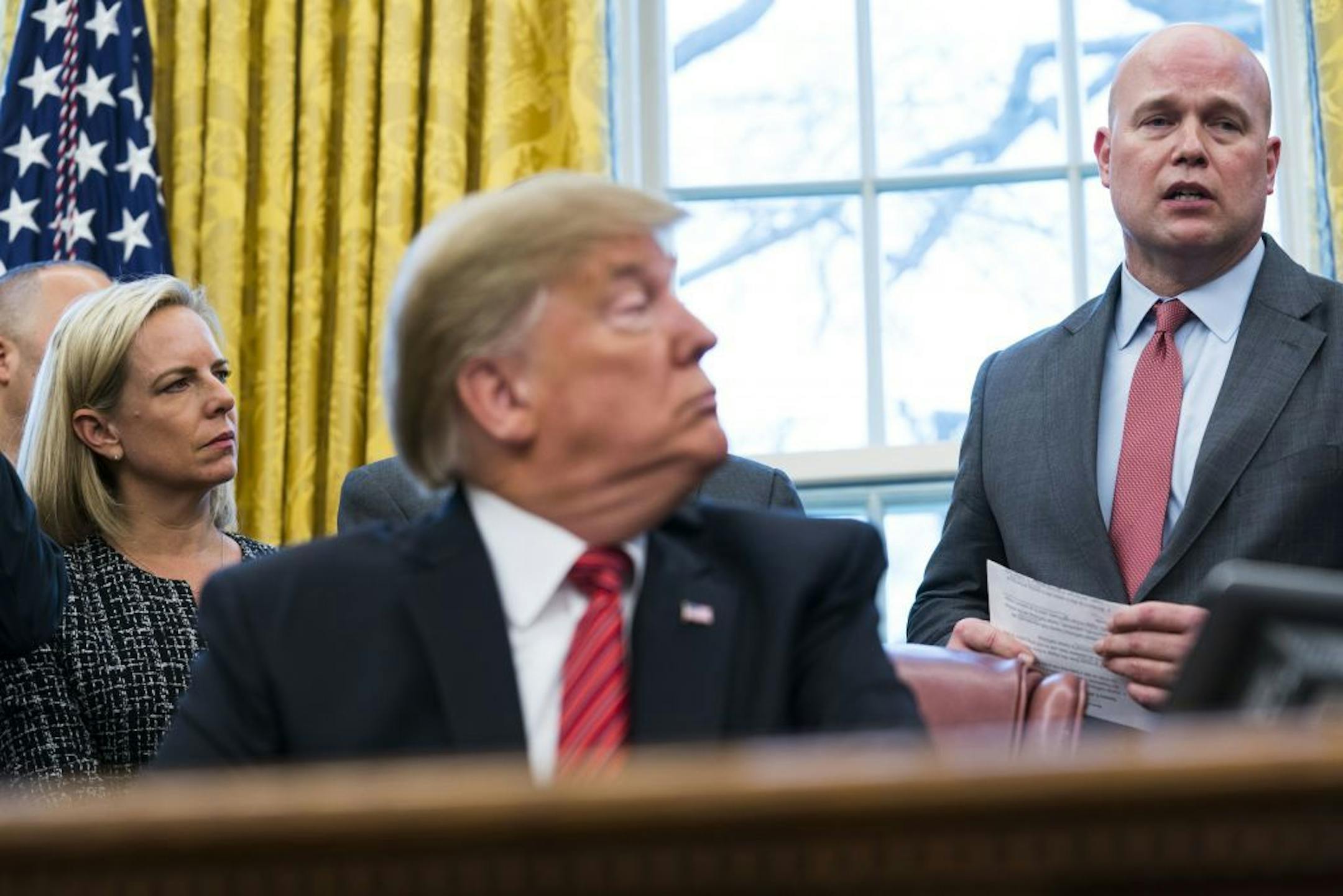 Acting Attorney General Matthew Whitaker speaks as President Donald Trump looks on at the signing ceremony for the Frederick Douglass Trafficking Victims Prevention and Protection Reauthorization Act, in the Oval Office of the White House, in Washington, Jan. 9, 2019. Wednesday also marked the 19th day of a partial government shutdown. At left is Homeland Security Secretary Kirstjen Nielsen.