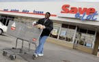 In this April 12, 2011 photo, shopper Andrew Boston leaves the Save-a-Lot grocery store with his purchases in Northfield, Ohio. Grocer Supervalu Inc.'