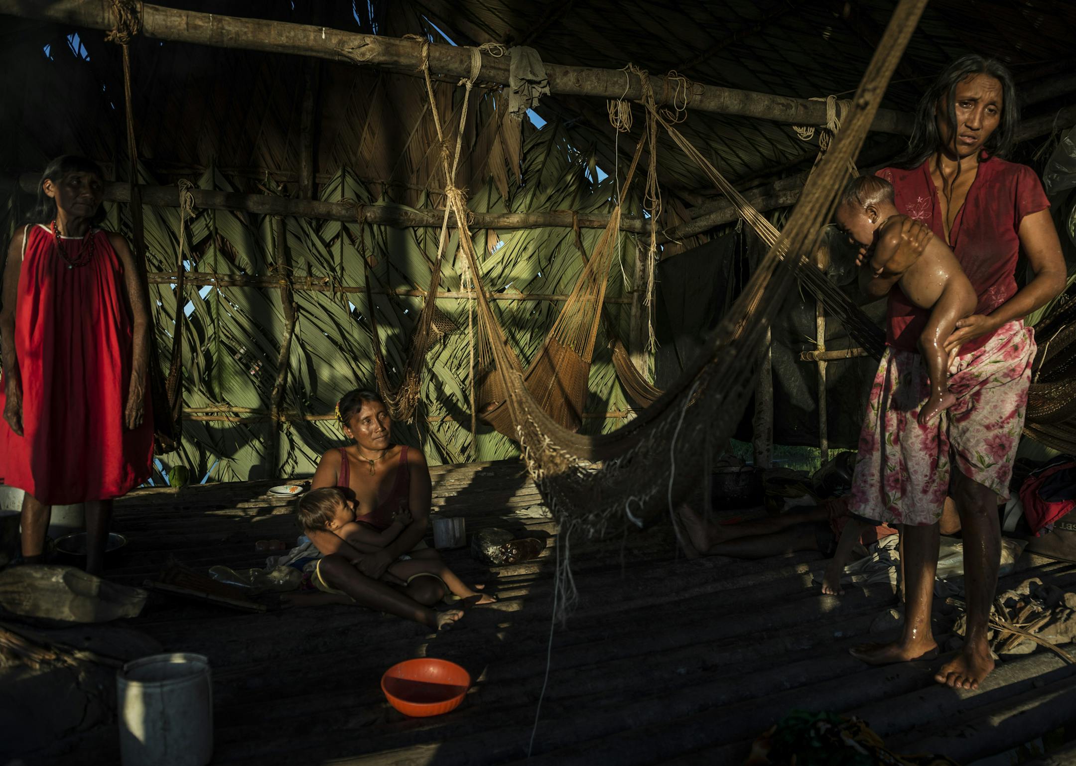Paulina Medina Beria, left, with her daughters-in-law, Norbely La Rosa, center, and Isbelia Freites La Rosa as the cared for their children, in Jobure de Guayo, Venezuela, Dec. 17, 2017. AIDS left Norbely La Rosa a widow. The settlement has been hit hard by AIDS. The disease is spreading rapidly through the indigenous Warao people of the Orinoco Delta, as government programs collapse. (Meridith Kohut/The New York Times)