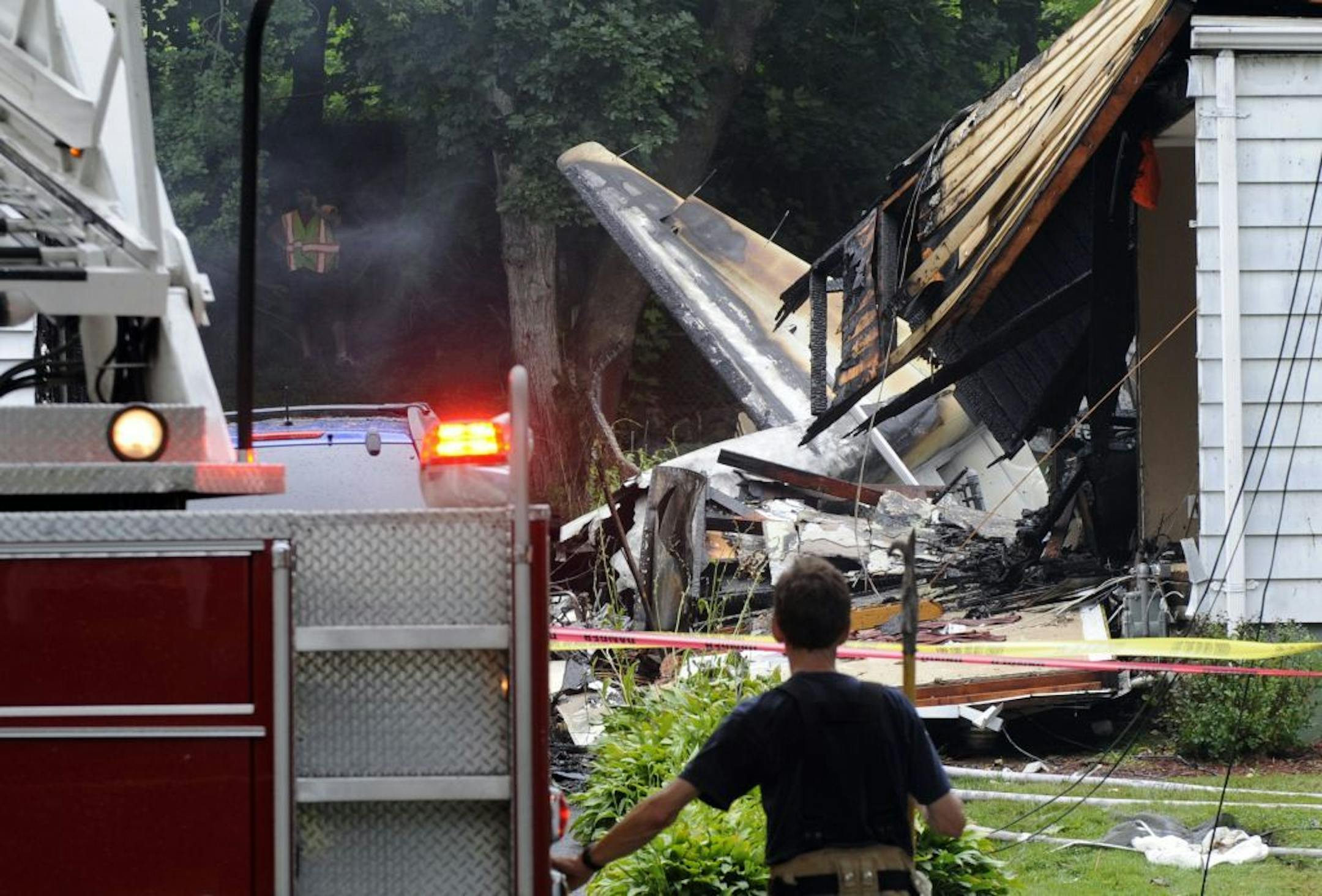 A firefighter surveys the scene of a small plane crash, Friday, Aug. 9, 2013, in East Haven, Conn. The multi-engine, propeller-driven plane plunged into a working-class suburban neighborhood near Tweed New Haven Airport, on Friday.